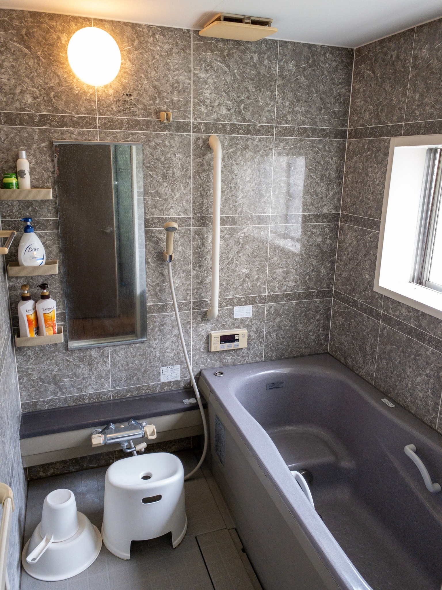 Bathroom with a bathtub, shampoo, conditioner, body soap.