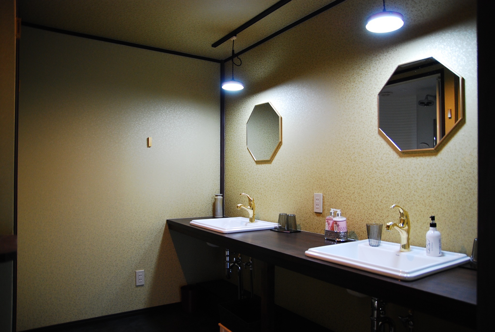 8角形の鏡と金柄の壁紙の洗面所